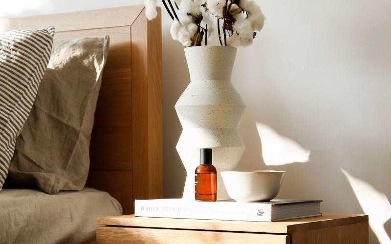 a vase with cotton stems on a bedside table