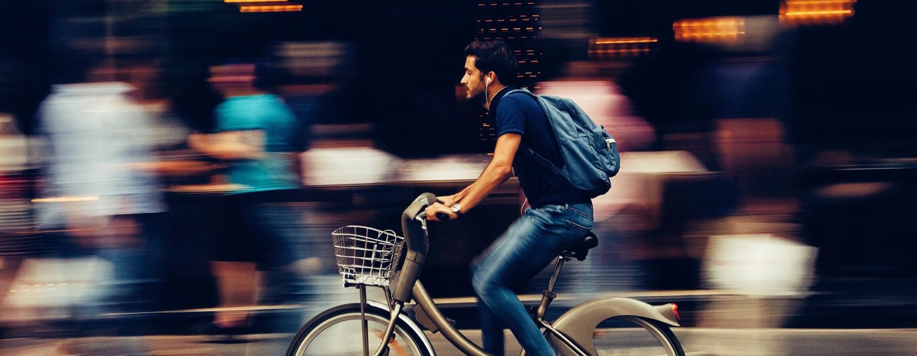 man riding a bicycle through town