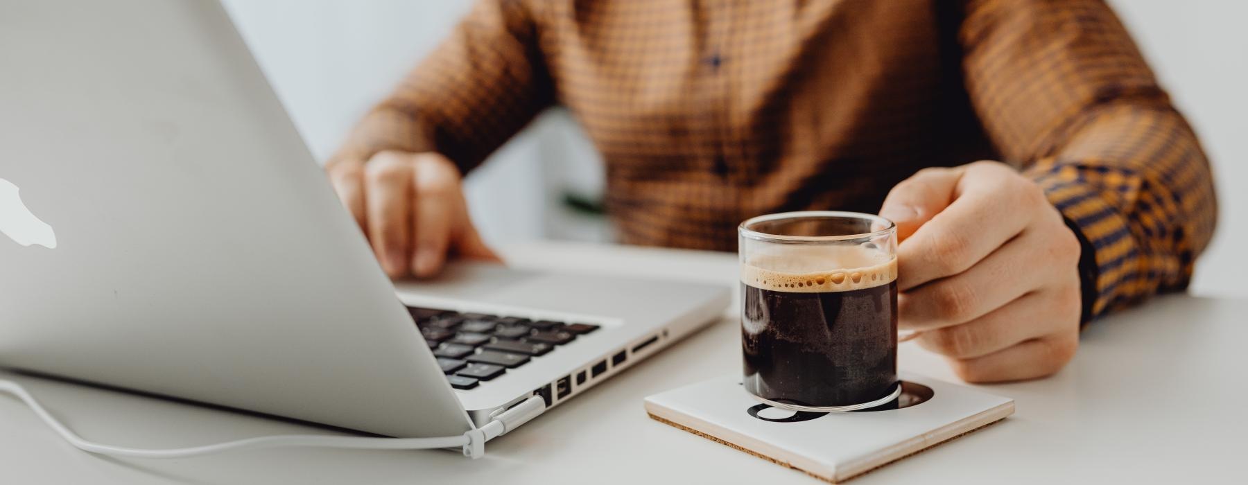 a man sitting at a table with a laptop and a cup of espresso