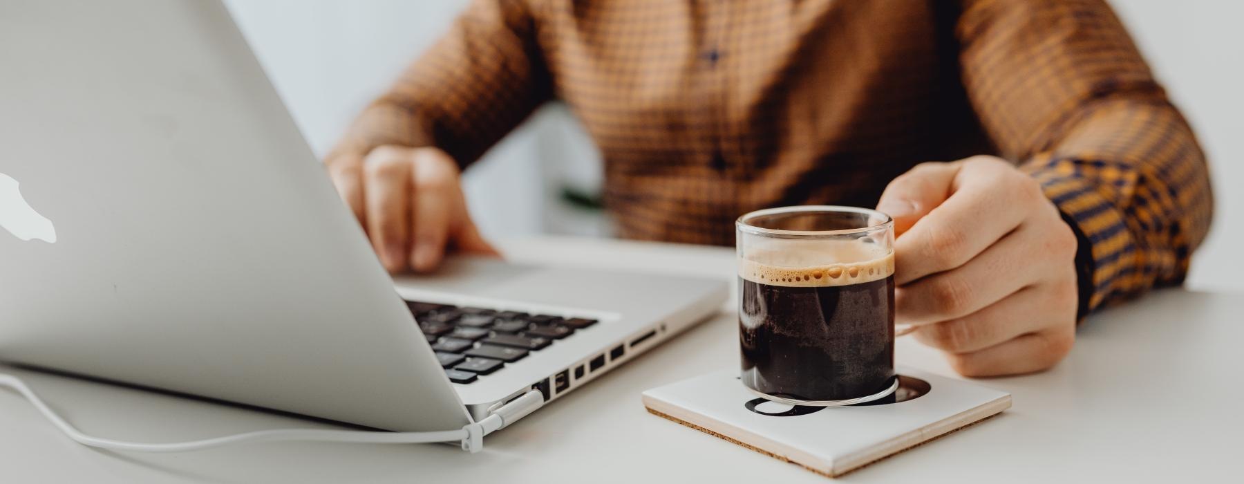 a man sitting at a table with a laptop and a cup of espresso